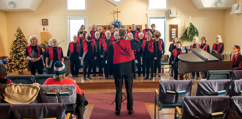 the choir, dressed in black clothes and red vests, performing the Christmas concert.